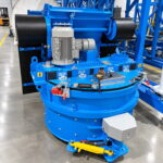 Máquina circular azul con rodillos negros a ambos lados, un motor central y un panel de control con botón rojo de emergencia